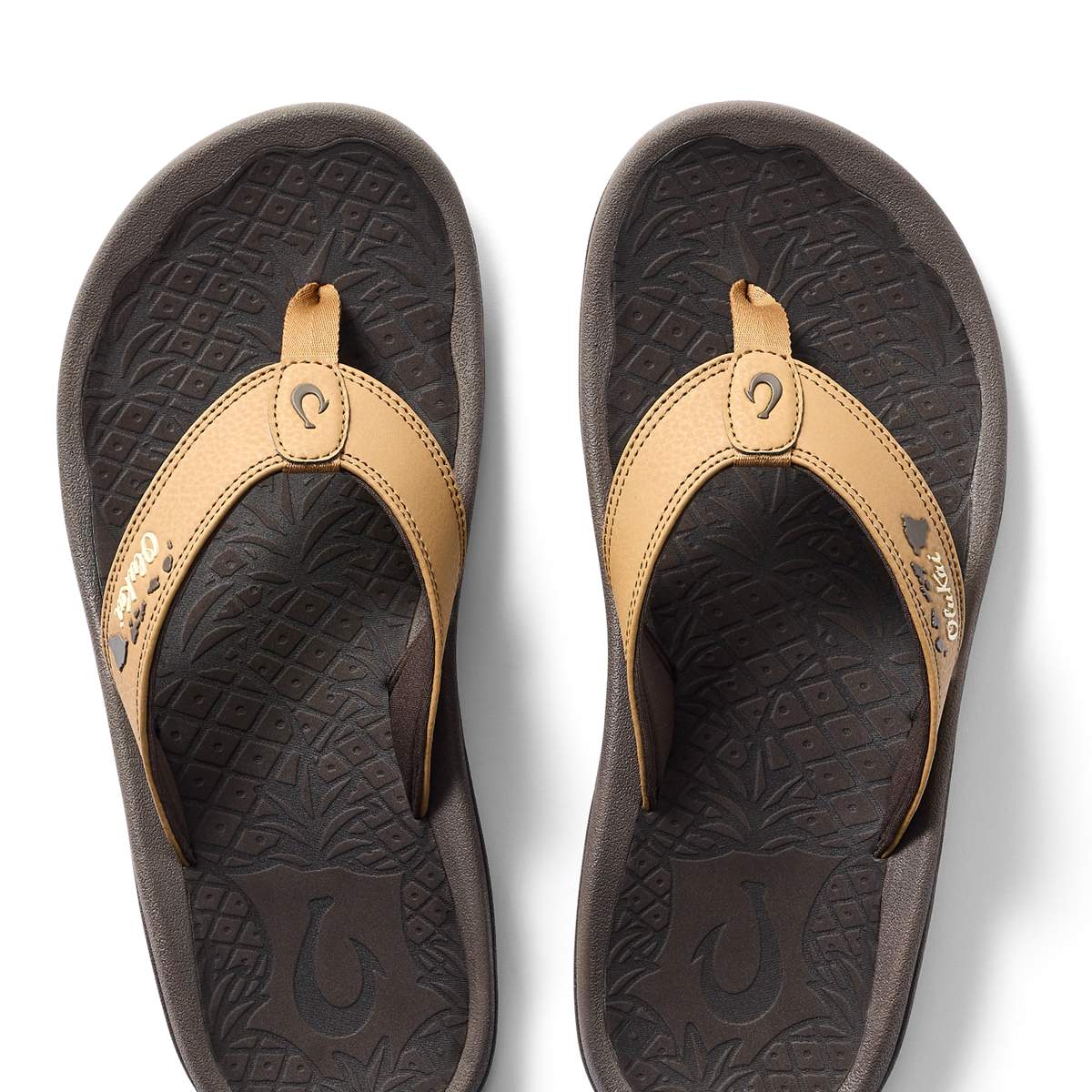 Tan and black thong sandals with decorative stitching and textured footbed, shown from above.