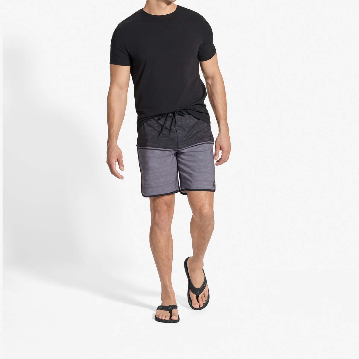 Man wearing black short-sleeve t-shirt and dark gray colorblock shorts with black sandals.