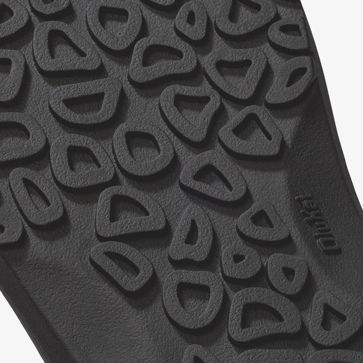Dark gray rubber sole with textured tread pattern featuring curved cutout design.