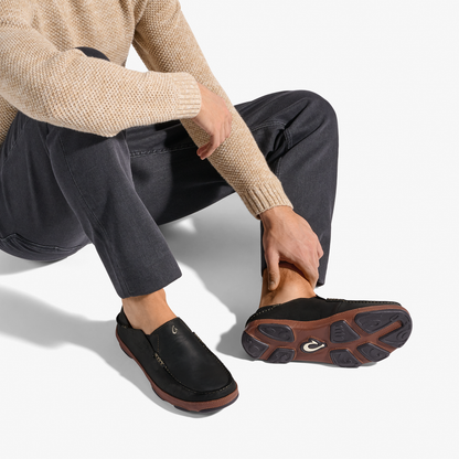 Black slip-on shoe with toffee-brown sole, worn with cream knit sweater and dark jeans.