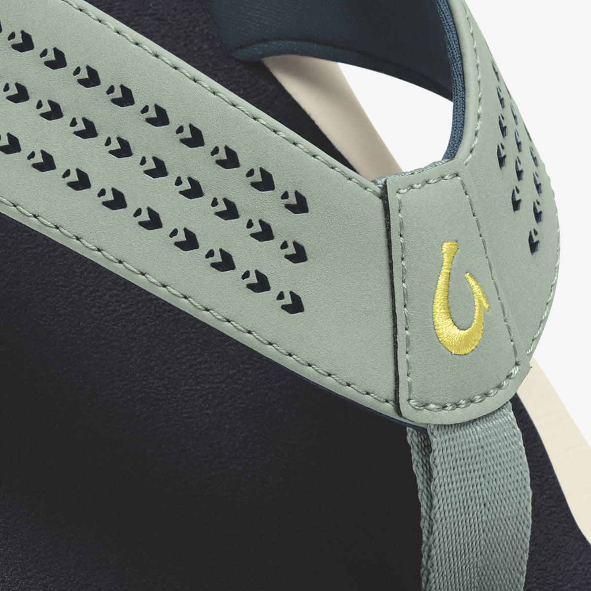 Seagreen sandal strap with perforated pattern, yellow embroidered logo, and dark blue interior lining visible.
