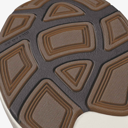 Shoe sole with tan and dark gray geometric tread pattern featuring rectangular and triangular shapes.