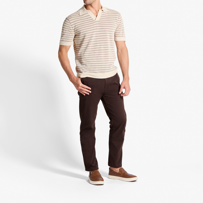Man wearing beige striped short-sleeve polo shirt and dark brown pants with brown slip-on shoes.
