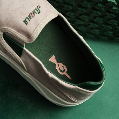 Cream and green canvas slip-on shoe with geometric logo design on green insole and brand text on heel tab.