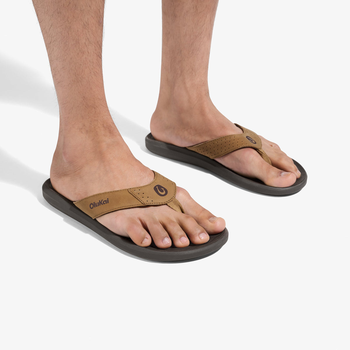Tan and dark gray thong sandals with perforated leather upper and black sole, shown on feet.