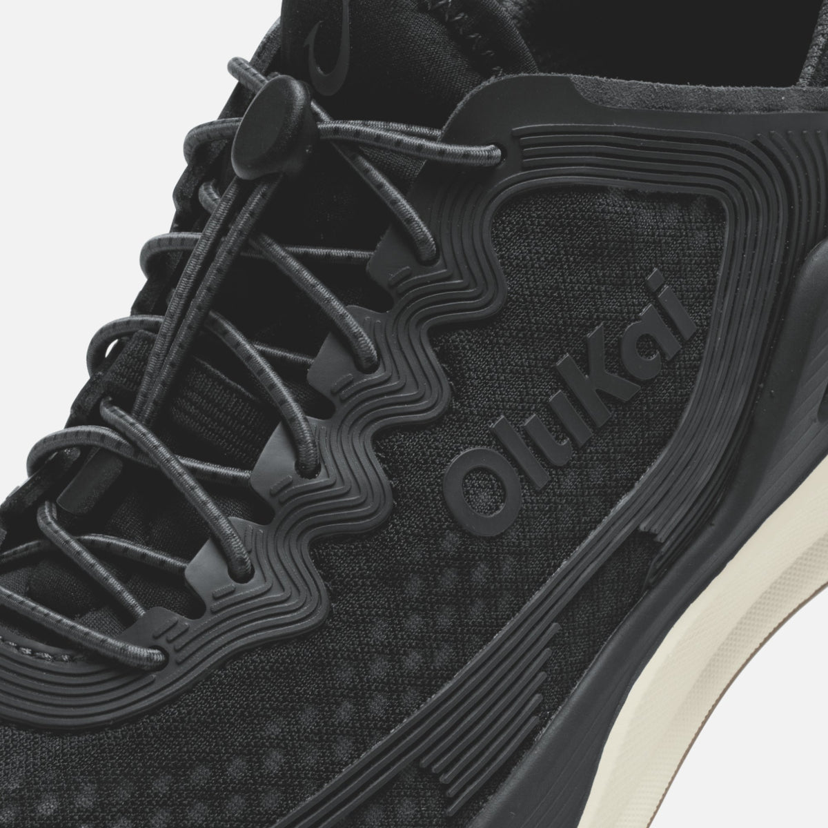 Black athletic shoe with mesh and synthetic upper, dark laces, ridged sole detail, and white midsole accent.