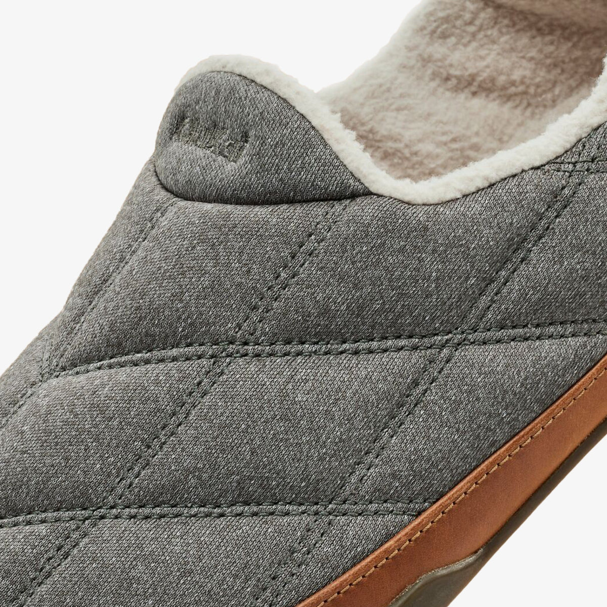 Gray quilted slipper with cream fleece lining and tan leather heel detail, shown from side view.