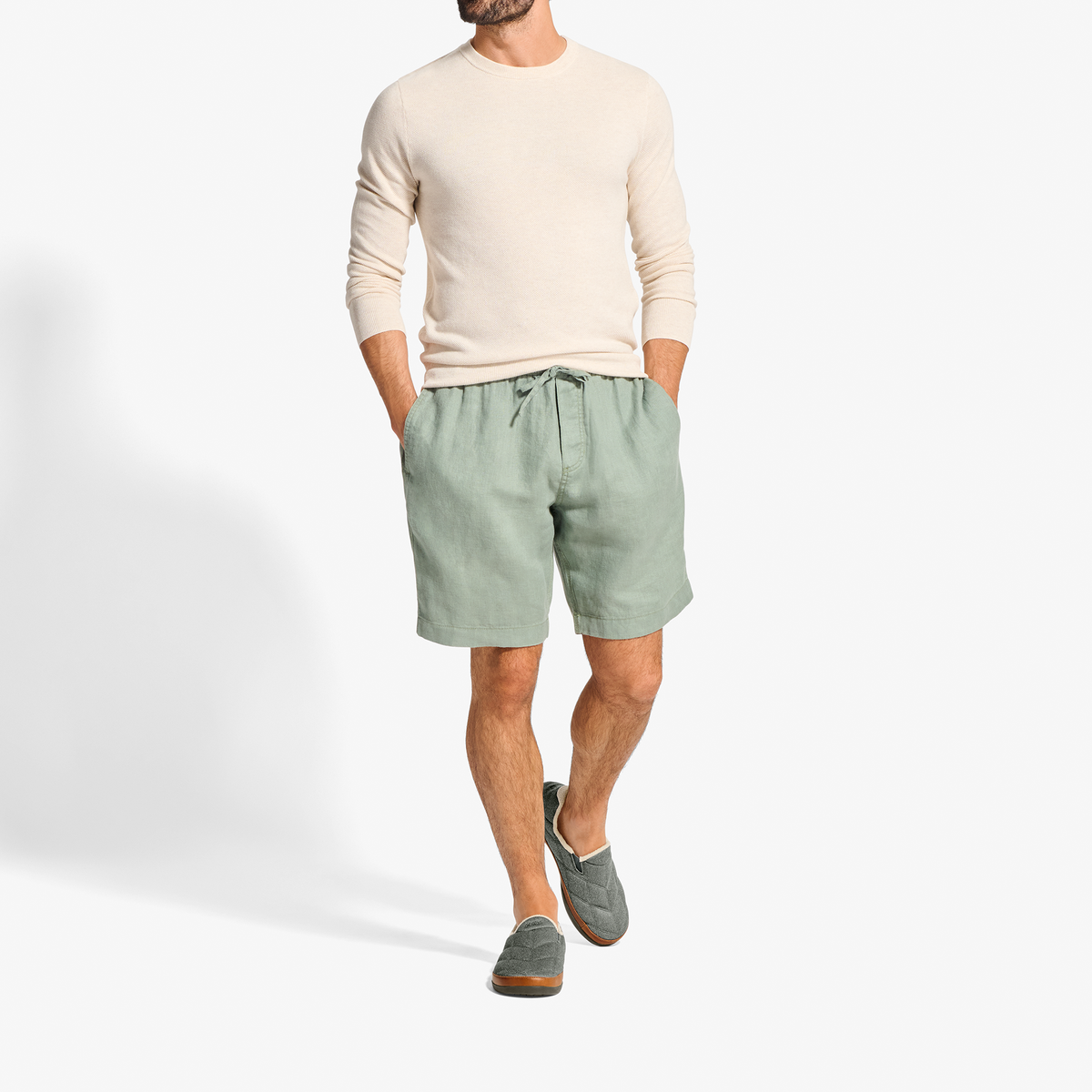 Man wearing cream long-sleeve shirt and sage green shorts with drawstring waist.