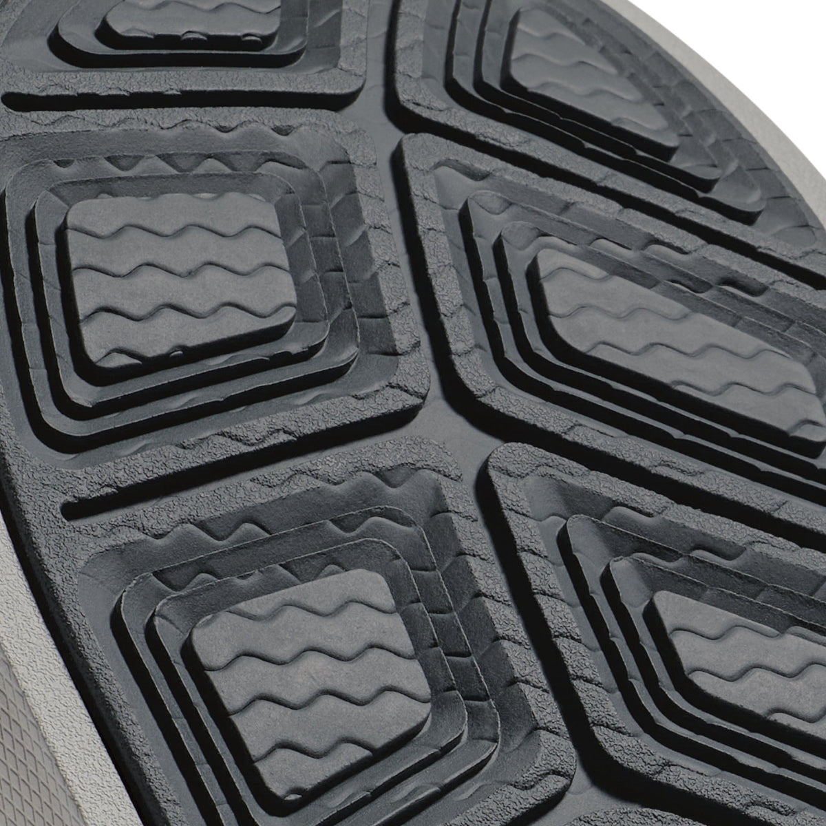 Close-up of gray and black automotive floor mat with wavy geometric tread pattern.