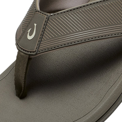 Brown sandal with textured upper strap, fabric toe post, and grooved sole with white hook logo detail.