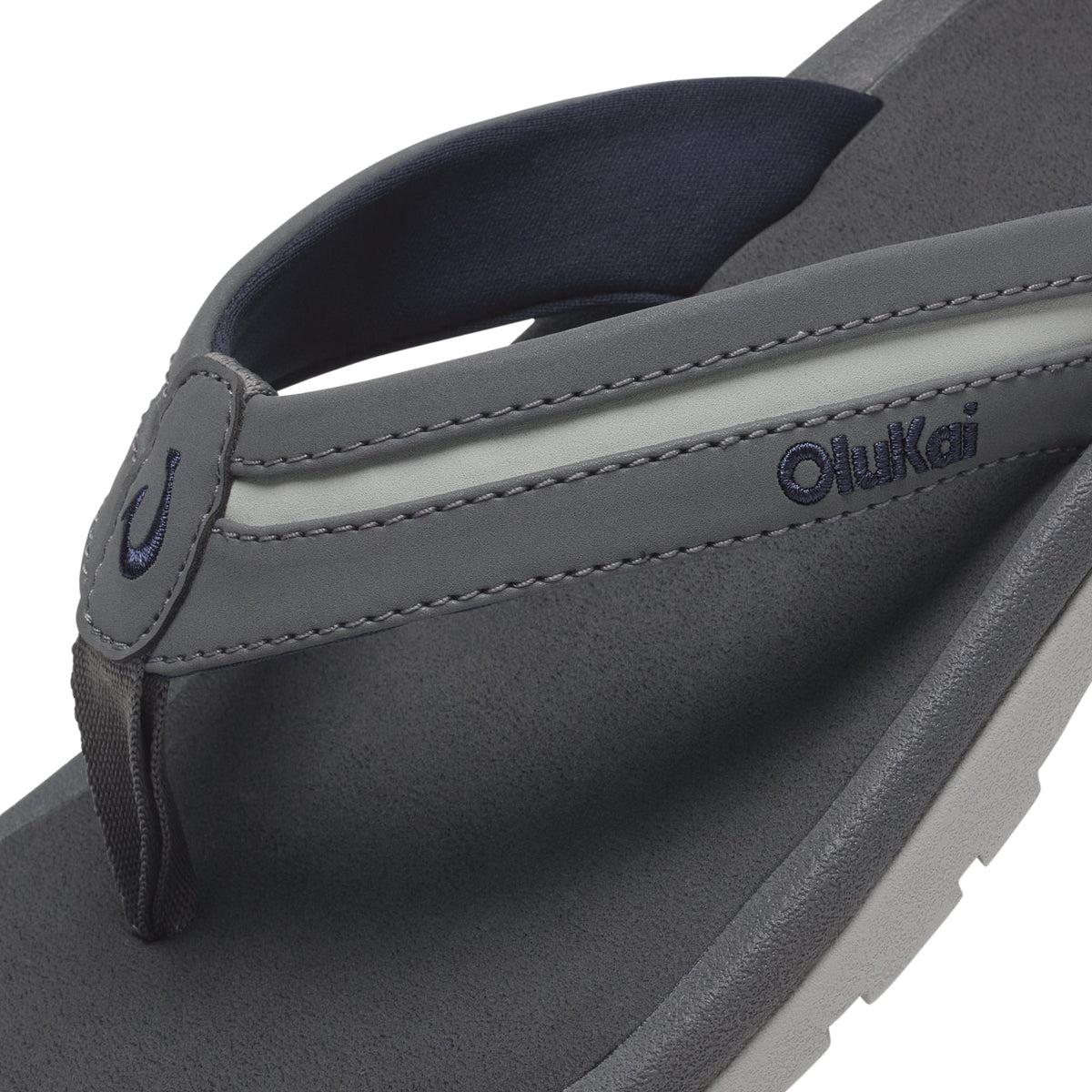 Grey and navy flip-flop with contoured footbed and cushioned thong strap featuring OluKai branding.