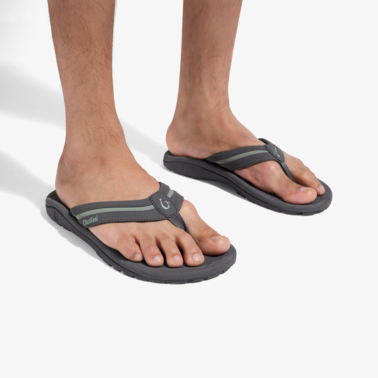 Man wearing grey and seagreen flip-flop sandals with cushioned soles and toe straps.