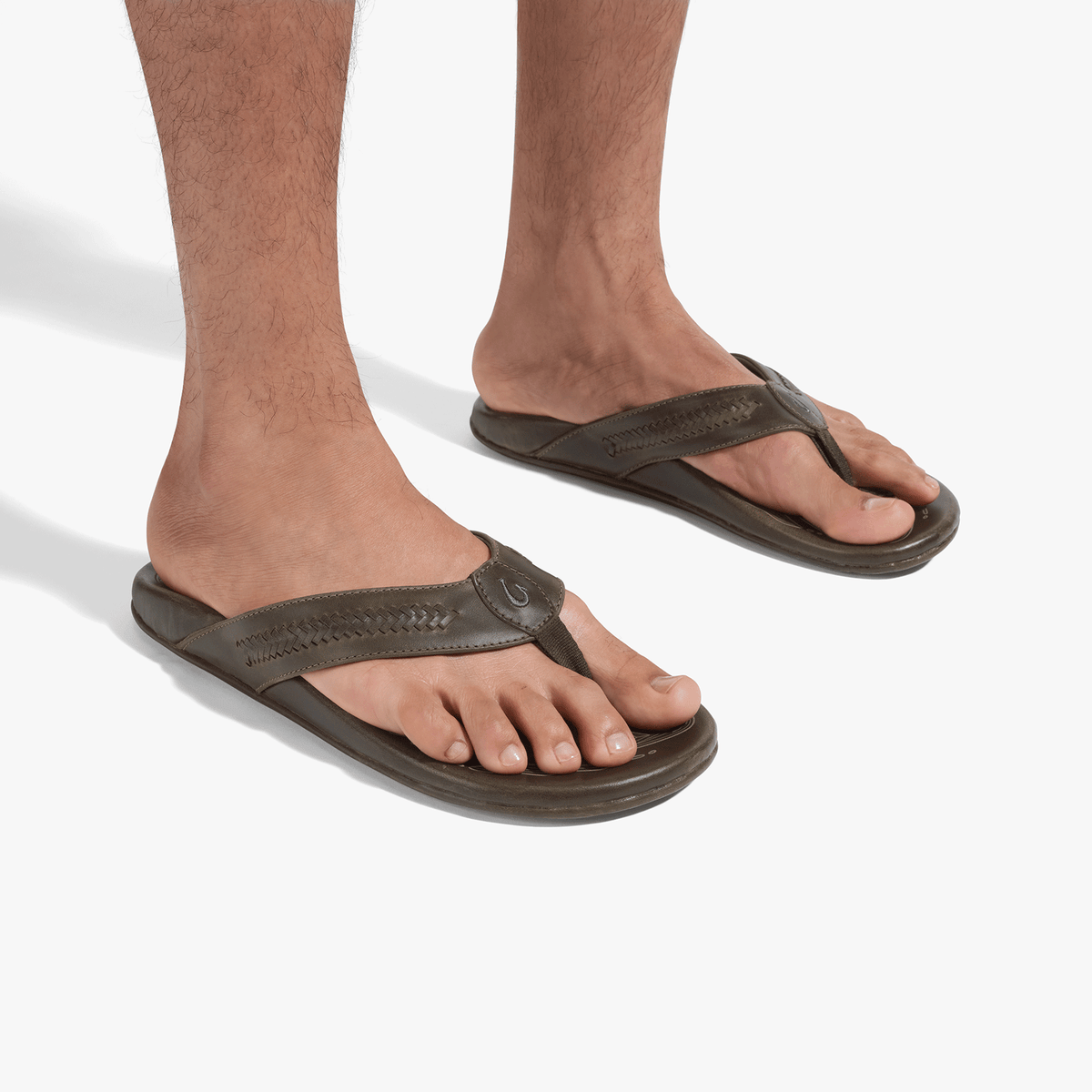 Tan thong sandals with contoured footbeds worn on male feet against white background.