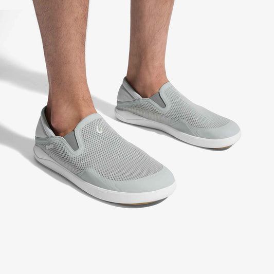 Grey and white mesh slip-on shoes with white sole, worn on feet against white background.