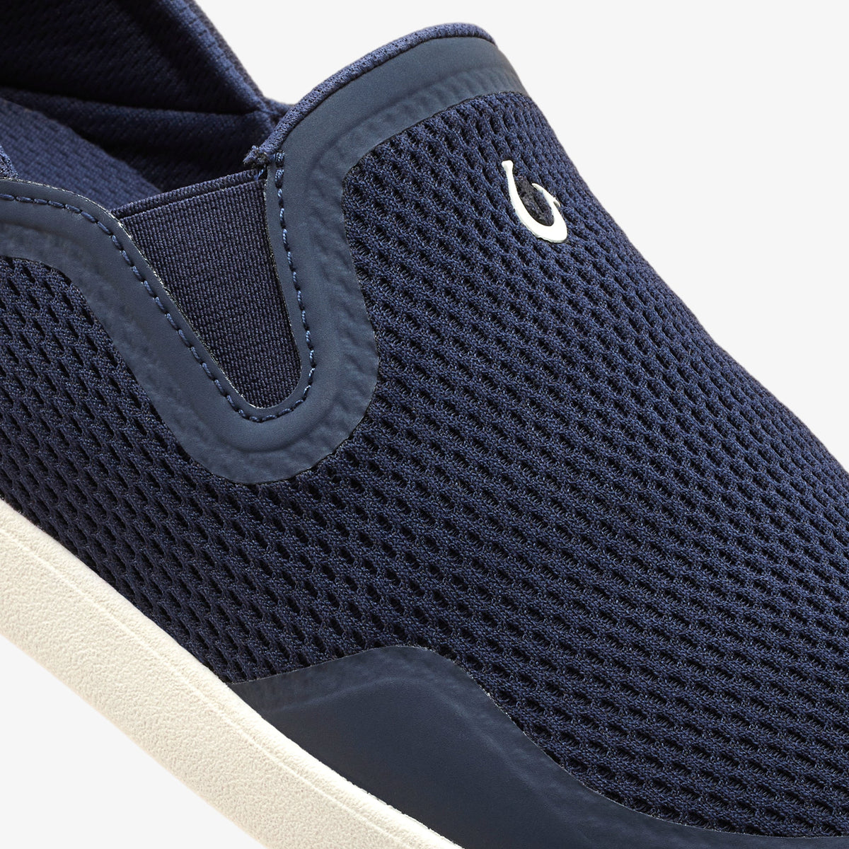 Trench blue slip-on shoe with textured mesh upper, elastic gusset, and white logo detail on heel counter.