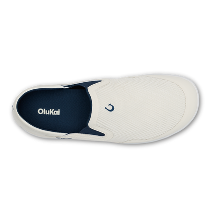 White slip-on sneaker with trench blue heel panel and OluKai branding, shown from above.