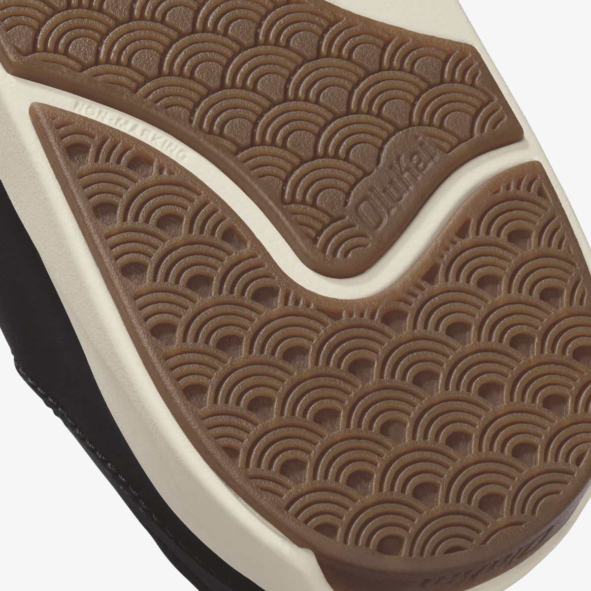 Tan and black shoe sole with geometric arc pattern and cream-colored midsole stripe.