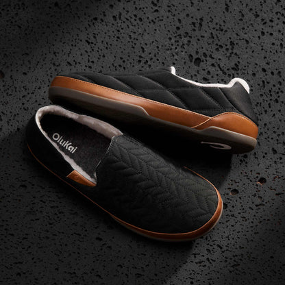 Black quilted slip-on slippers with tan leather sole and fleece lining, shown from top and side angles.