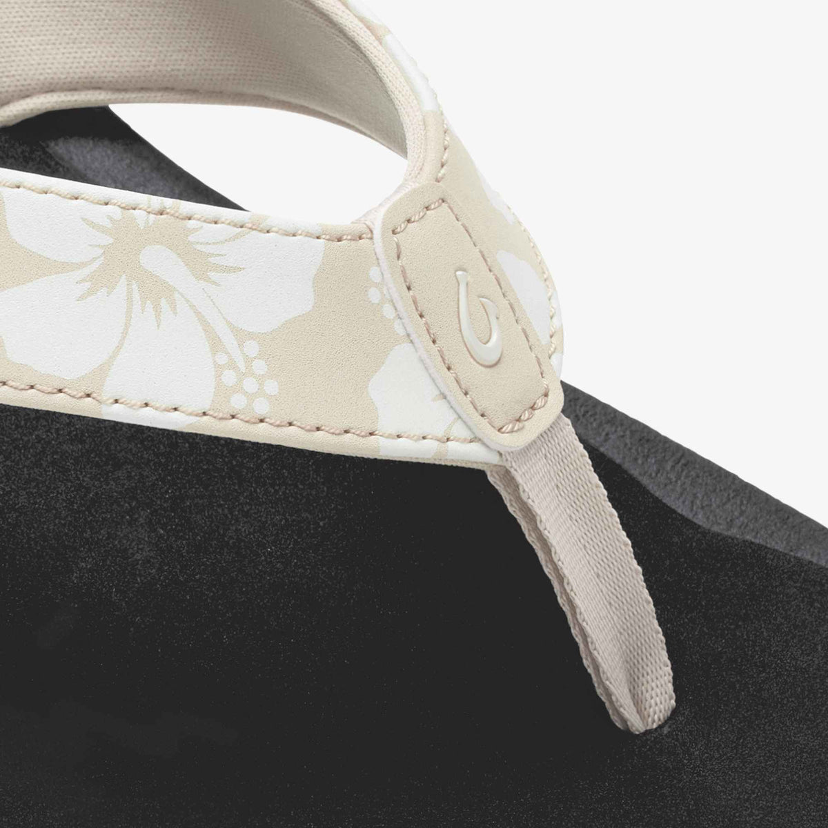 Black sandal with cream tapa/pua floral-patterned strap and white fabric toe post detail.