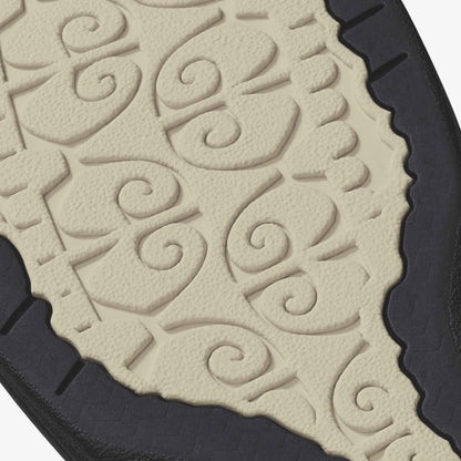 Cream-colored tapa cloth with embossed spiral and leaf patterns bordered by scalloped edges and black trim.
