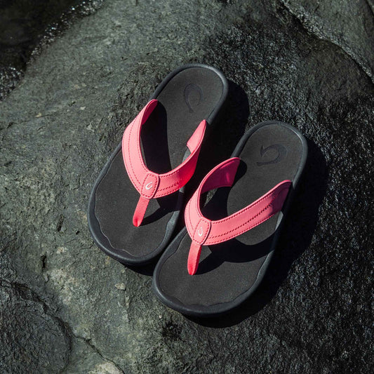 Pair of hot pink and black flip-flop sandals with cushioned soles displayed on a concrete surface.