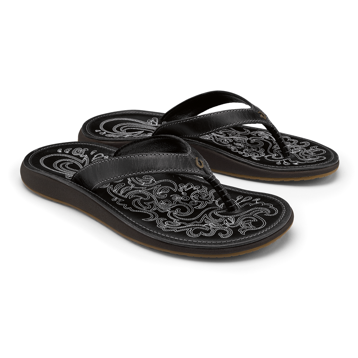 Pair of black leather flip-flops with ornate white embroidered patterns on footbeds and straps.