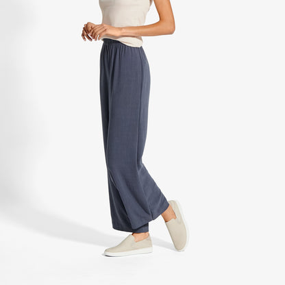 Woman wearing navy wide-leg pants with elastic waistband and cream slip-on leather shoes.