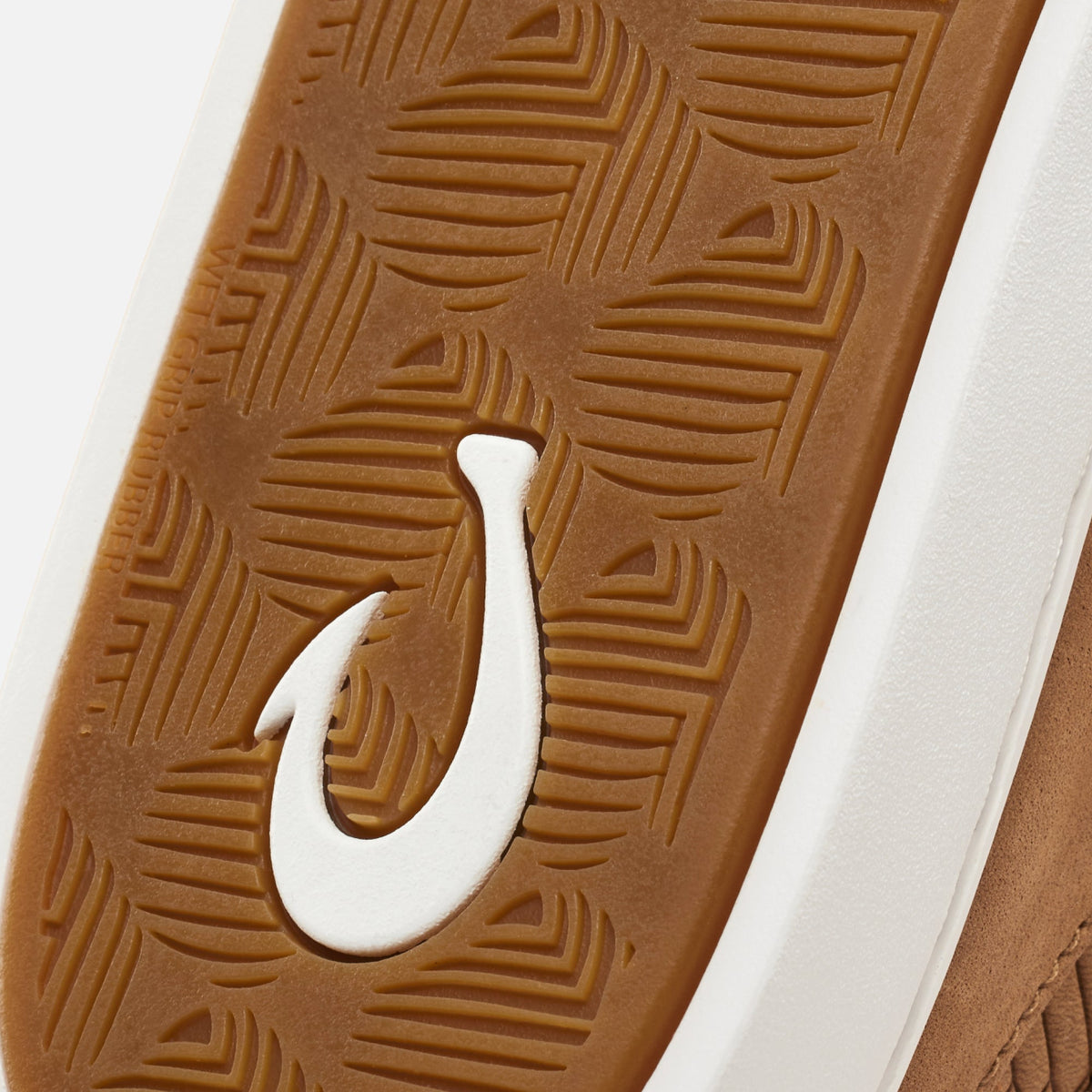 Tan leather shoe sole with geometric tread pattern and white curved logo detail.