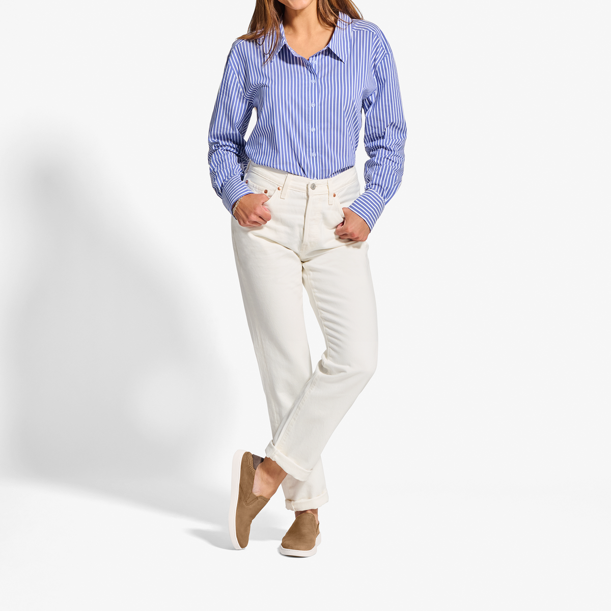Woman wearing blue striped button-up shirt, cream pants, and tan leather slip-on shoes.