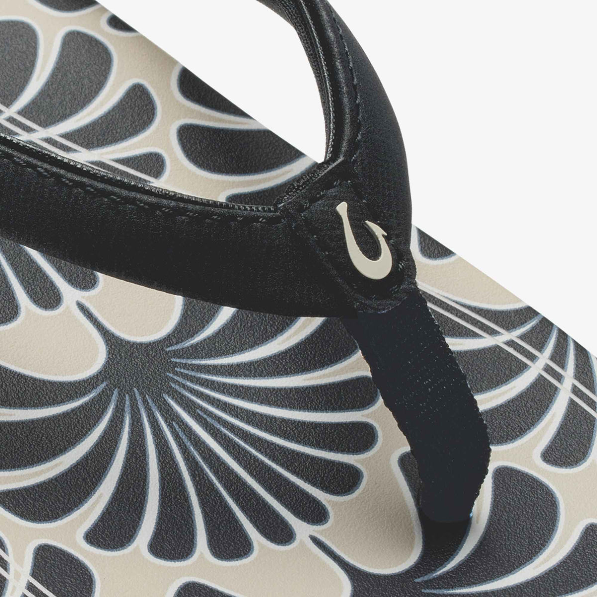 Black leather shoulder bag with cream and gray geometric shell pattern and curved handle detail.