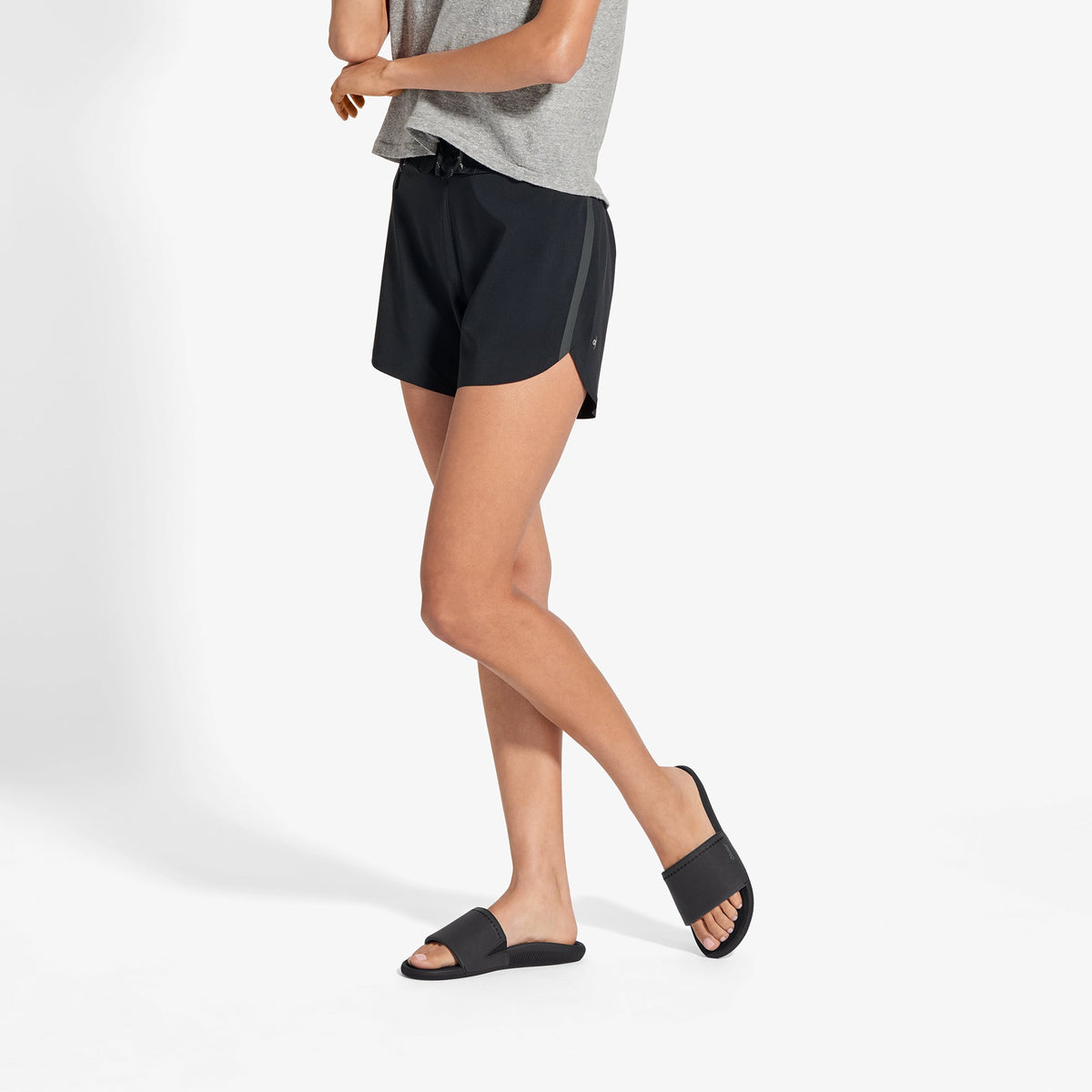 Black slide sandal with wide strap worn with black shorts and gray t-shirt.
