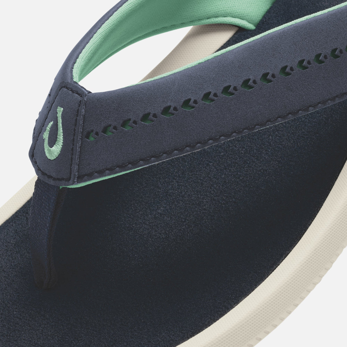 Dark navy flip-flop with mint green strap, cream sole, and decorative stitching detail.
