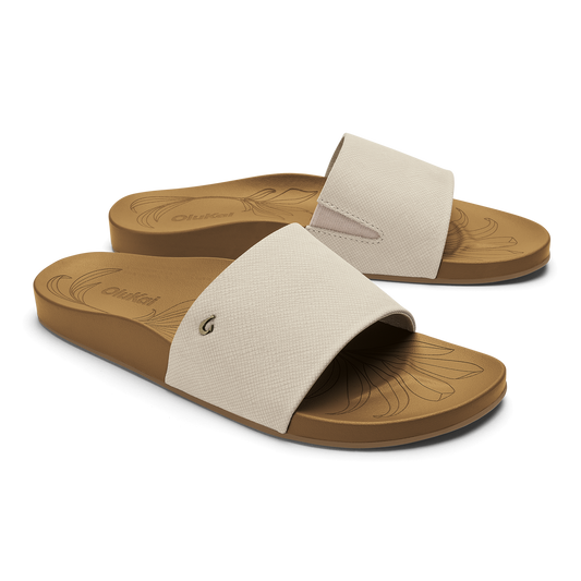 White crosshatch slide sandals with tan soles featuring engraved tapa pattern design.