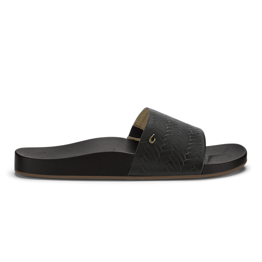 Black slide sandal with woven texture upper, tan footbed, and metallic accent buckle.