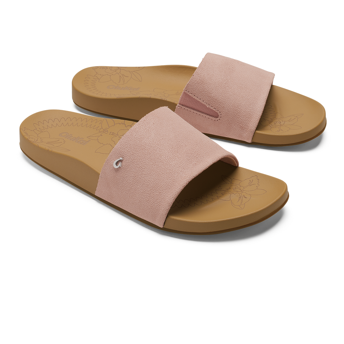 Pair of slide sandals with soft pink suede uppers and warm sand-colored rubber soles featuring embossed floral design.
