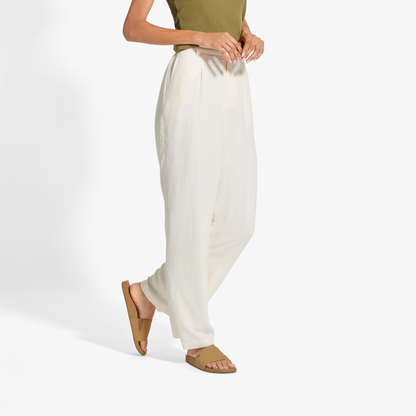 Person wearing olive green sleeveless top and cream-colored wide-leg pants with tan sandals.