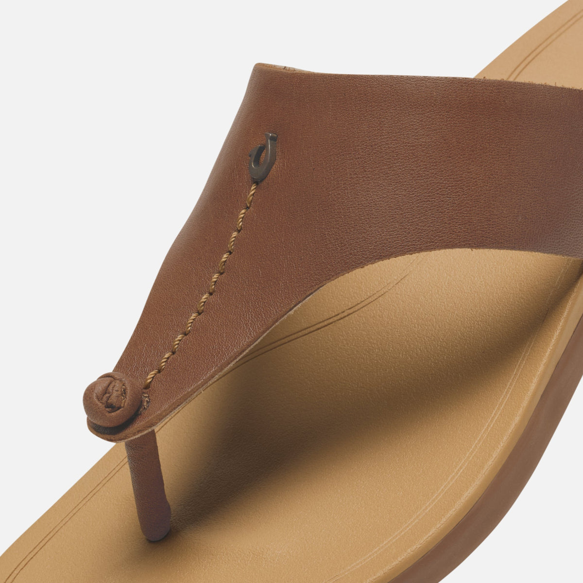 Toffee-brown leather thong sandal with warm sand-colored sole and decorative stitched strap detail.