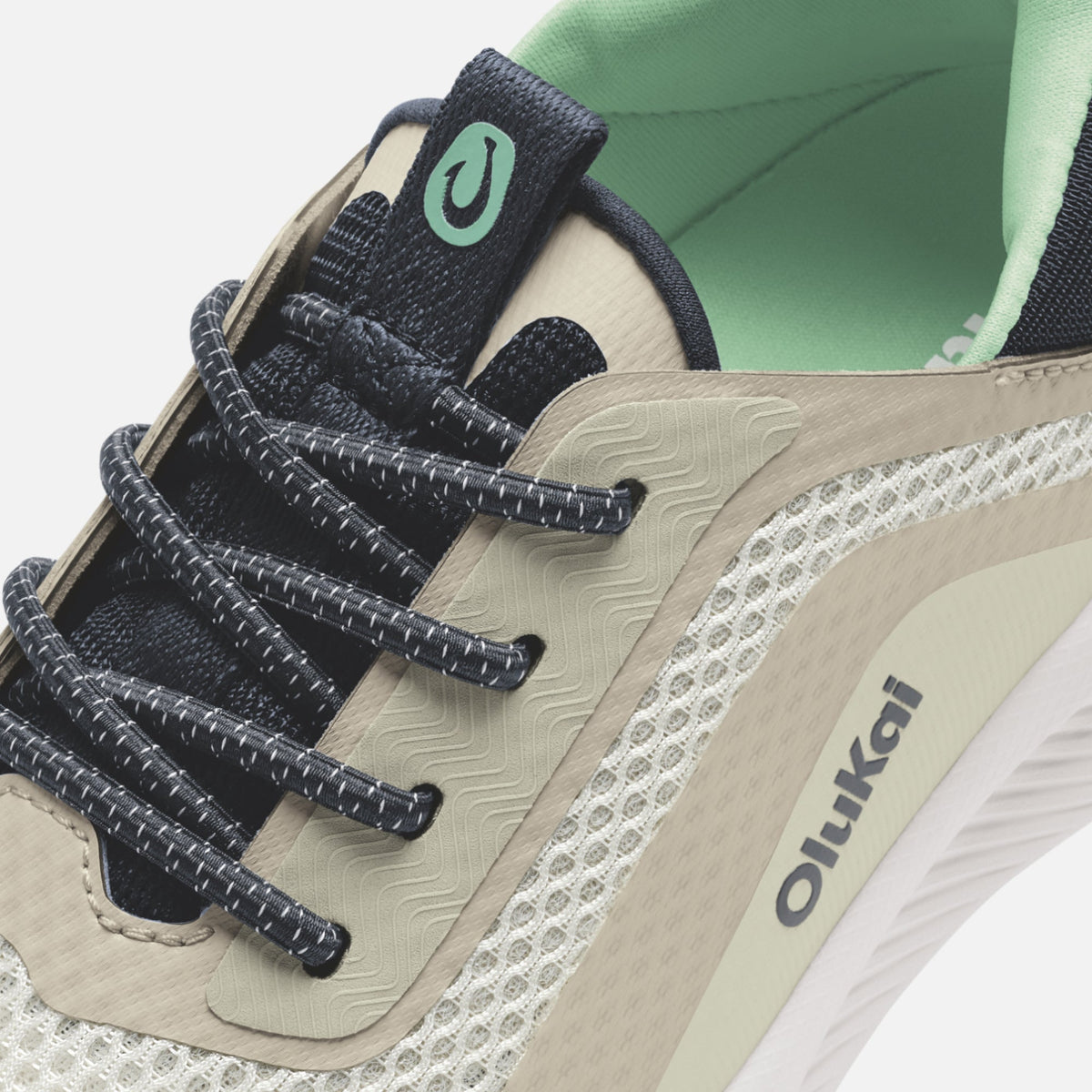 White and beige sneaker with black laces, mint green tongue tab, and white sole.