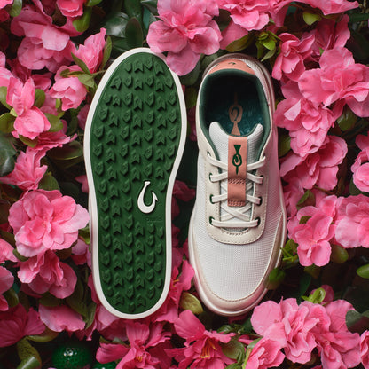 White canvas sneaker with white laces and rust-colored heel tab, shown from top and bottom sole views with green patterned so