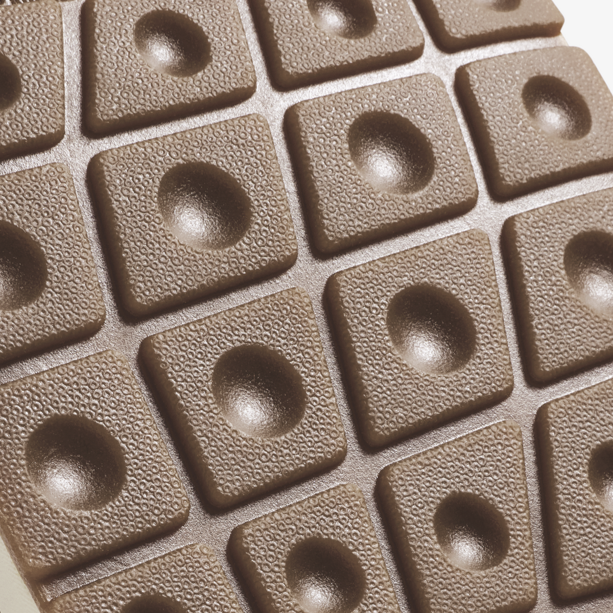 Beige textured tiles with raised square edges and hemispherical bowl indentations, arranged in a grid pattern.