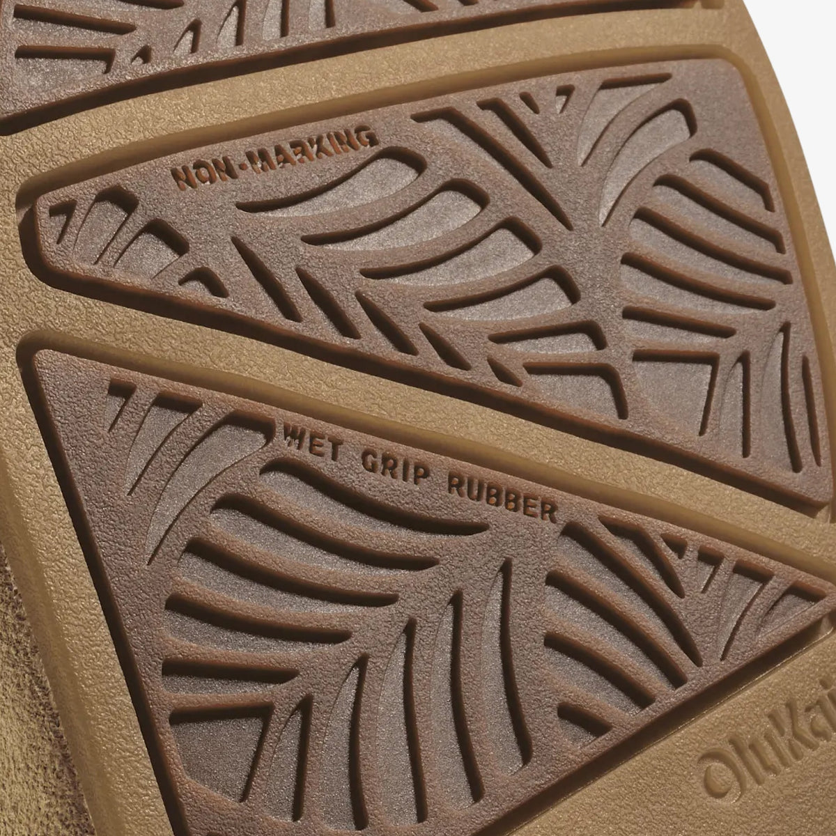 Tan rubber sole showing non-marking tread on top section and wet grip rubber pattern on bottom section.