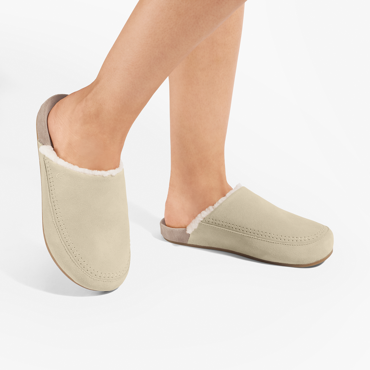 Cream suede mule slipper with taupe grey heel and sherpa lining, shown on feet in profile.
